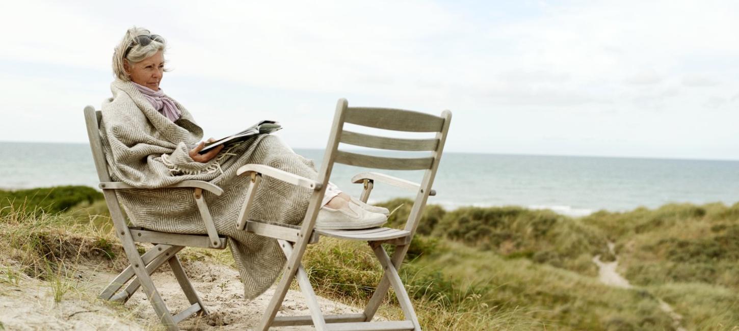 Frau liest in einem Stuhl am Strand in Westjütland an der Dänischen Nordsee