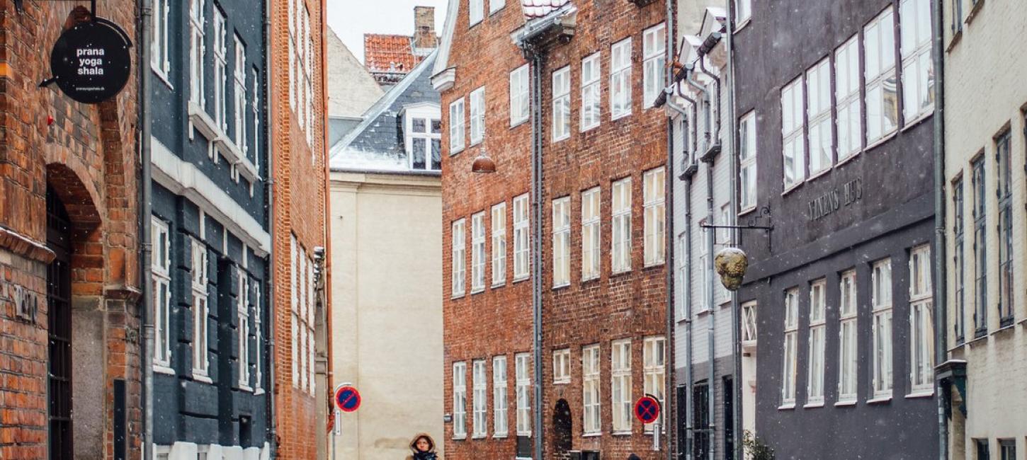 A woman cycles down snowy Magstræde in Copenhagen, Denmark