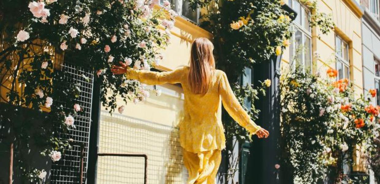 A girl in a yellow dress walks down a rose-lined Copenhagen street