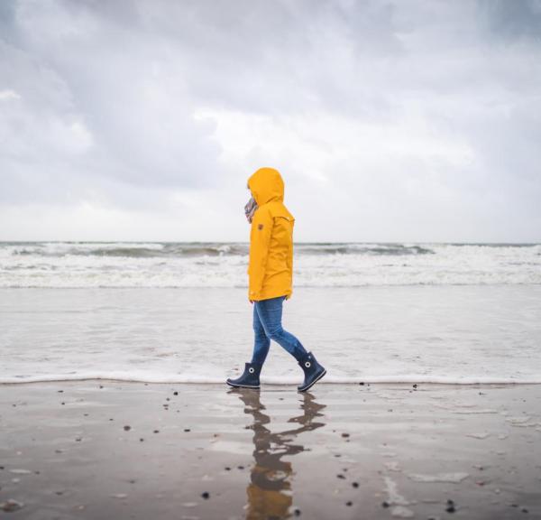 Spaziergänger in gelber Regenjacke am Strand von Blåvand an der Dänischen Nordsee