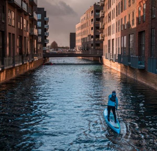 A man paddleboarding in a canal in Copenhagen, Denmark