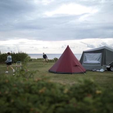 Familie spielt vor einem Camping-Zelt am Strand in Dänemark